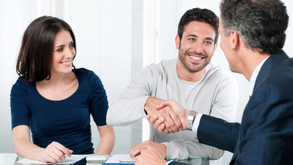 A happy smiling couple shaking hand with their advisor