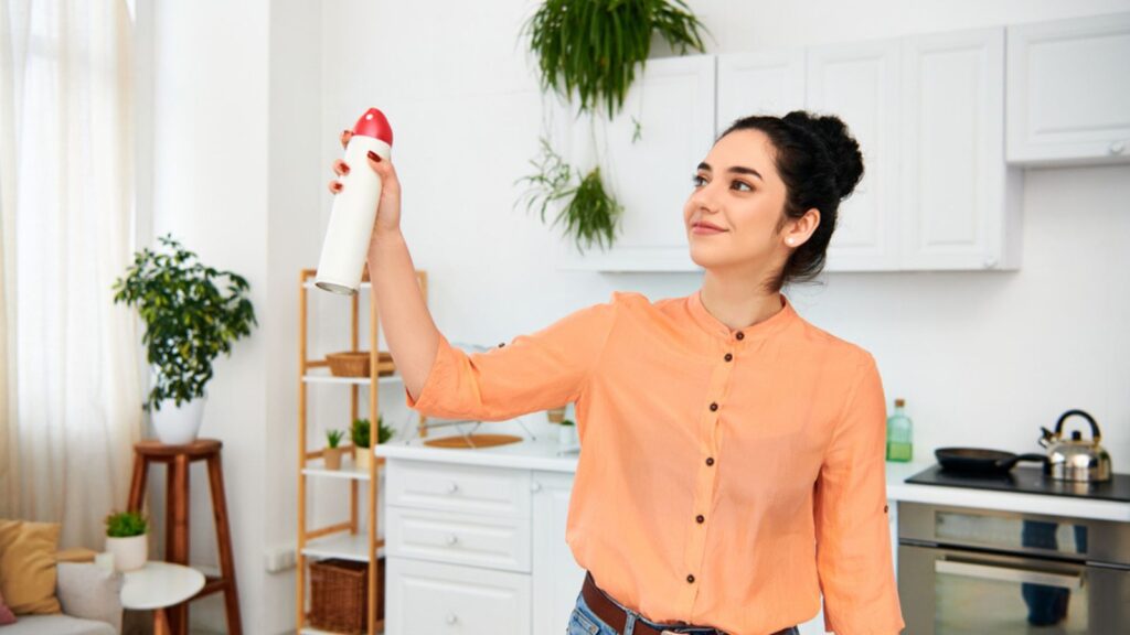 A stylish woman in casual attire holding a red and white object, possibly cleaning her home air freshener