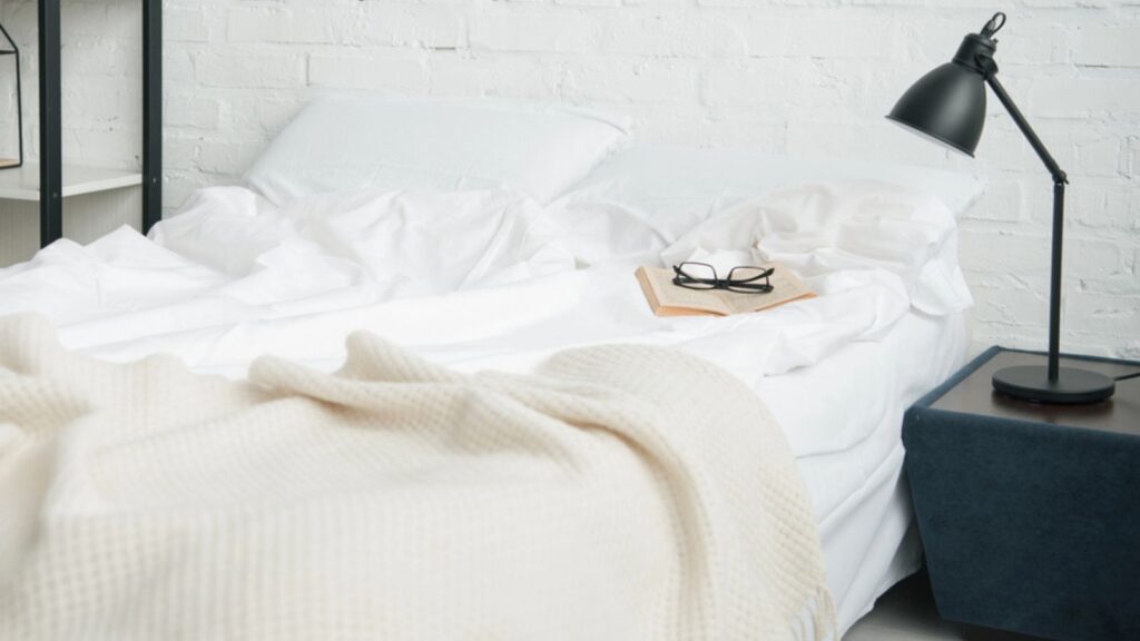 Bedroom with rack, white bed and lamp on nightstand