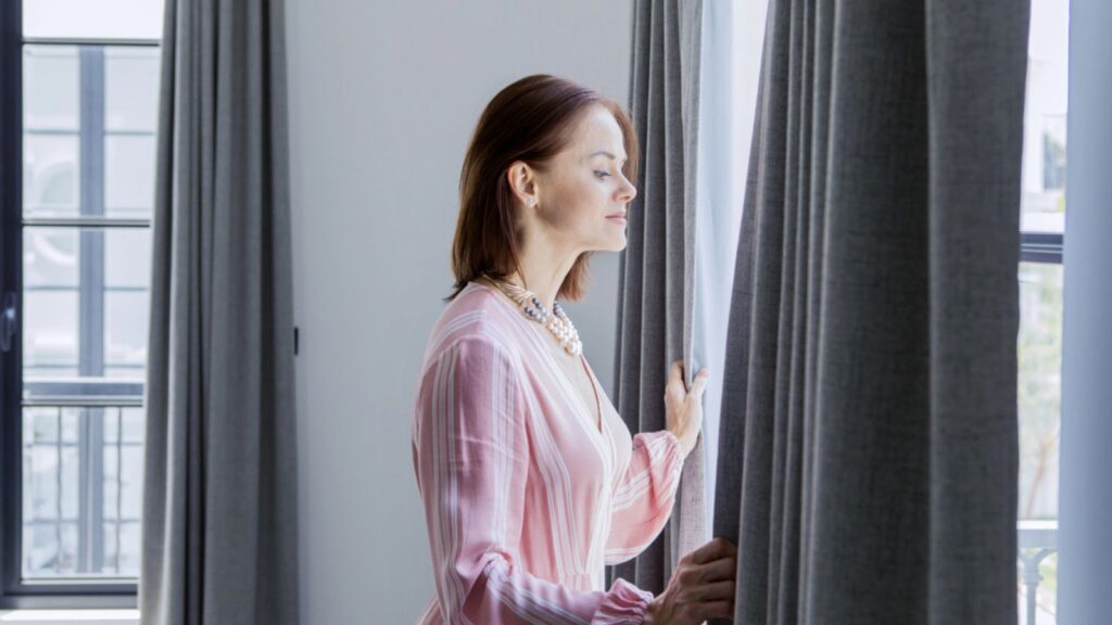 Caucasian woman looking out the window curtain