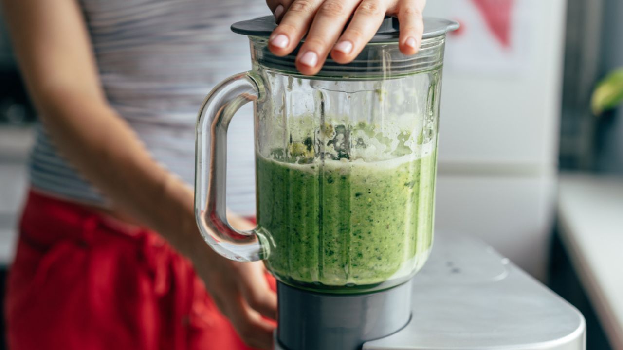 Close-up blender process. Cooking a green spring smoothie. Mixing in a blender bowl.