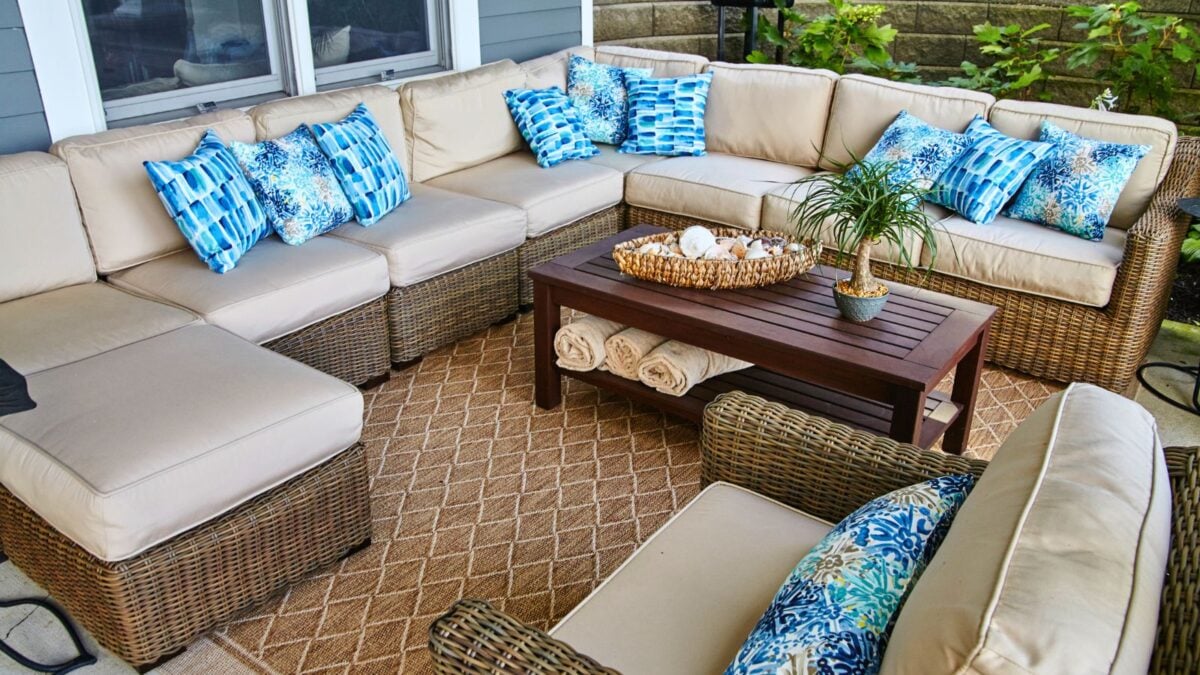 Cozy coastal-inspired outdoor patio with elegant wicker furniture and blue cushions.