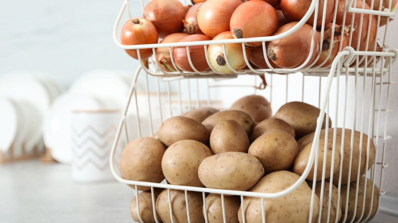 Container with potatoes and onions on grey kitchen counter. Orderly storage