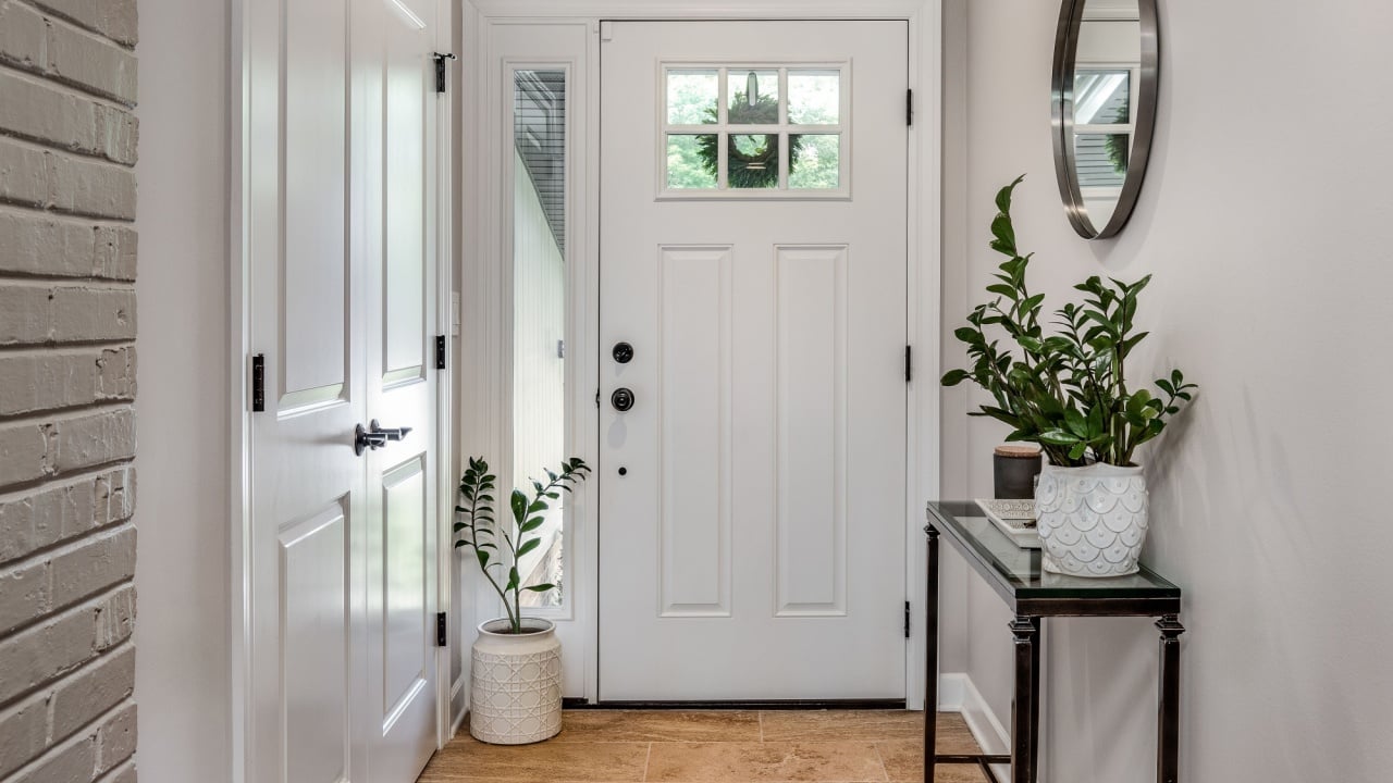 cozy entryway with brown and brick walls, hardwood flooring, decorations, and a white front door with windows