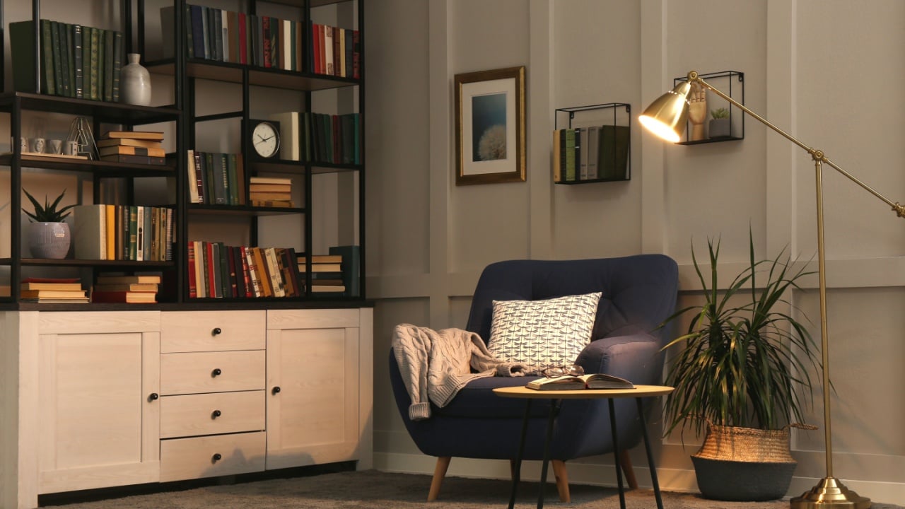 Cozy home library interior with collection of different books on shelves and comfortable place for reading