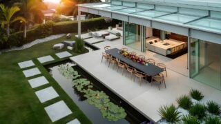 day view of luxurious modern house exterior with dining space and garden
