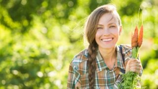 Gardening - Woman with organic carrots in a vegetable garden