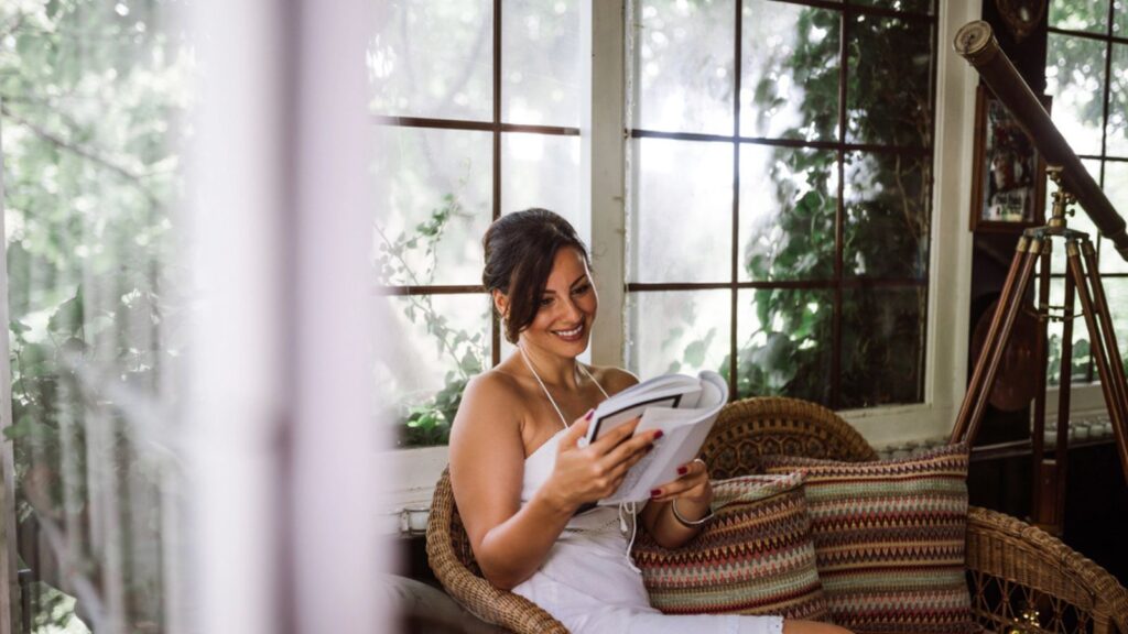 Gorgeous woman reading a book in garden sunroom or conservatory.