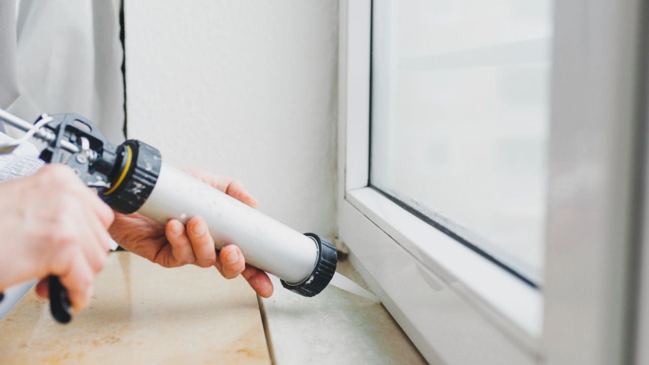 Hands of worker using a silicone tube for repairing of window