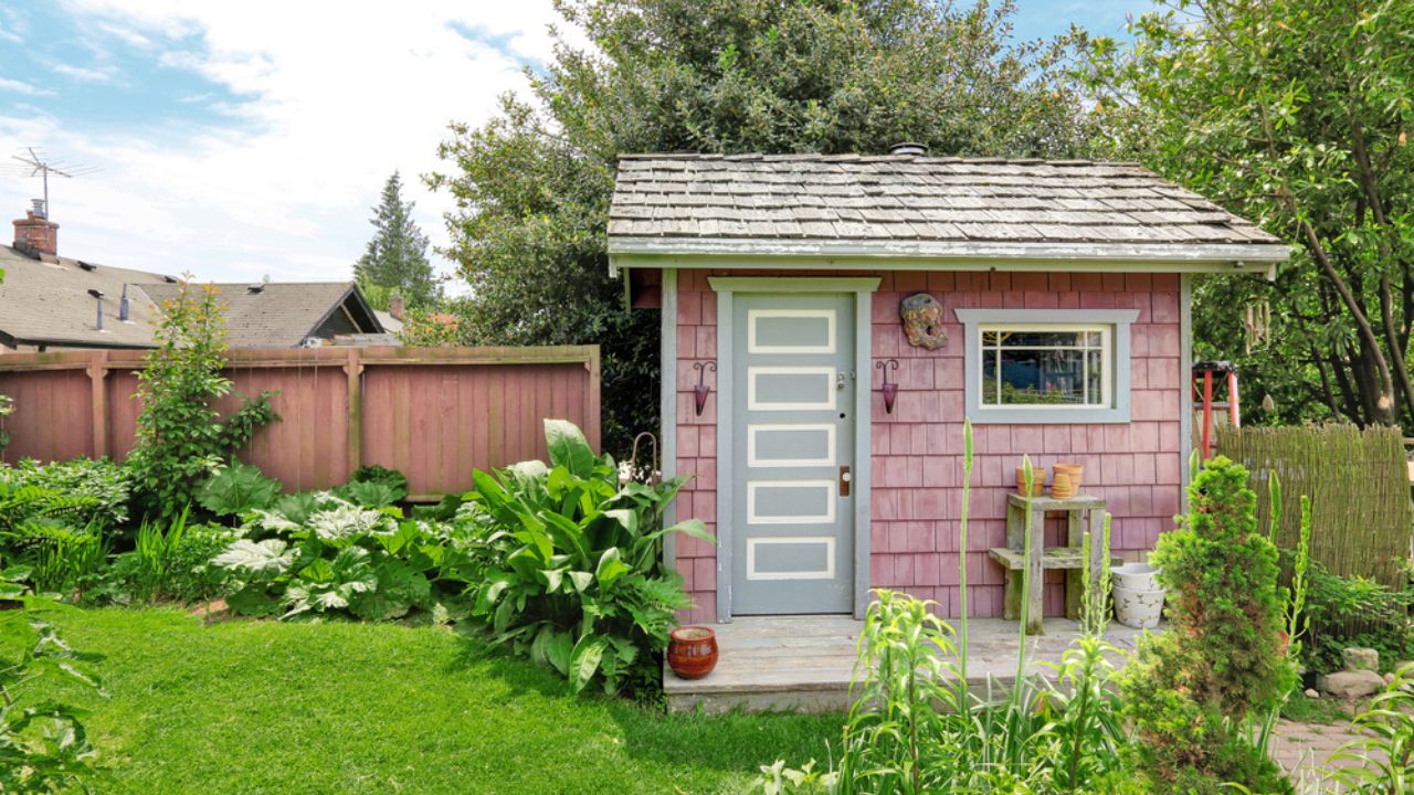 Home garden on backyard with small red barn shed and red wooden fence