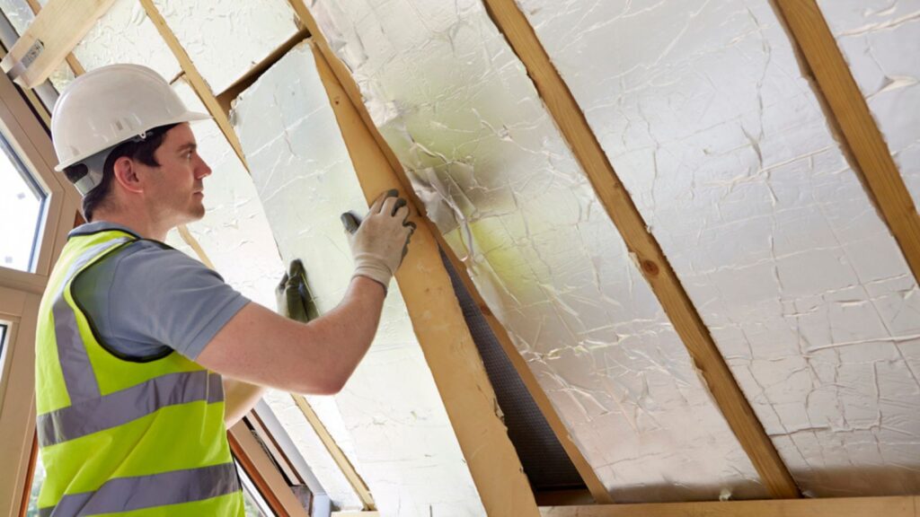 Man Builder Fitting Insulation Into Roof Of New Home