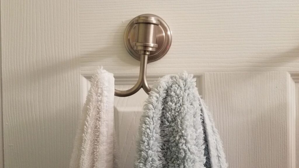 Metal towel hanger on white door in bathroom