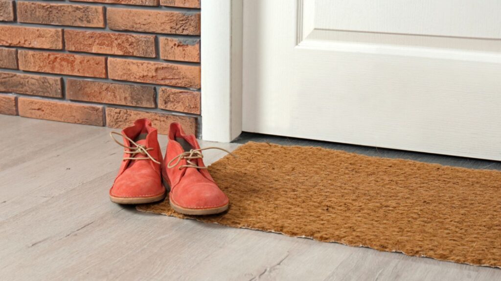 New clean mat with shoes near entrance door