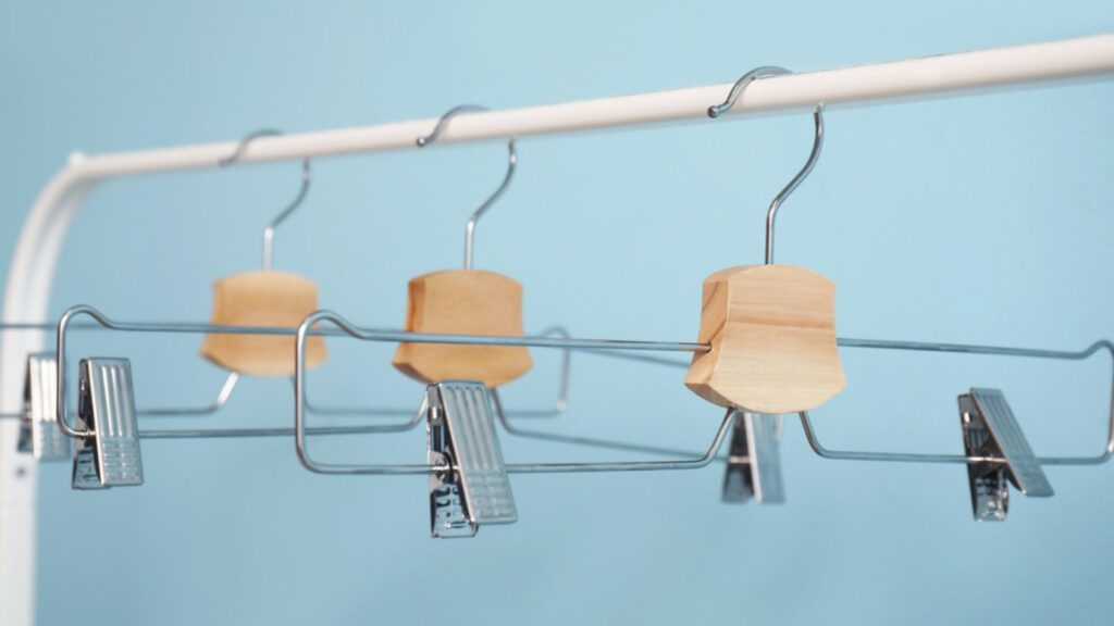 Rack with metal clothes hangers on blue background