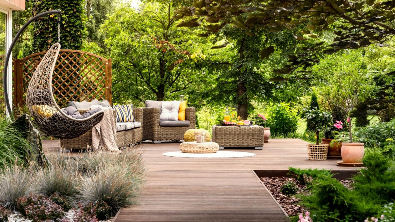 Beautiful wooden terrace with garden furniture surrounded by greenery on a warm, summer day