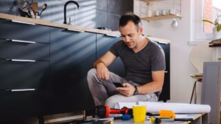 Man working on a new kitchen installation and using a smart phone