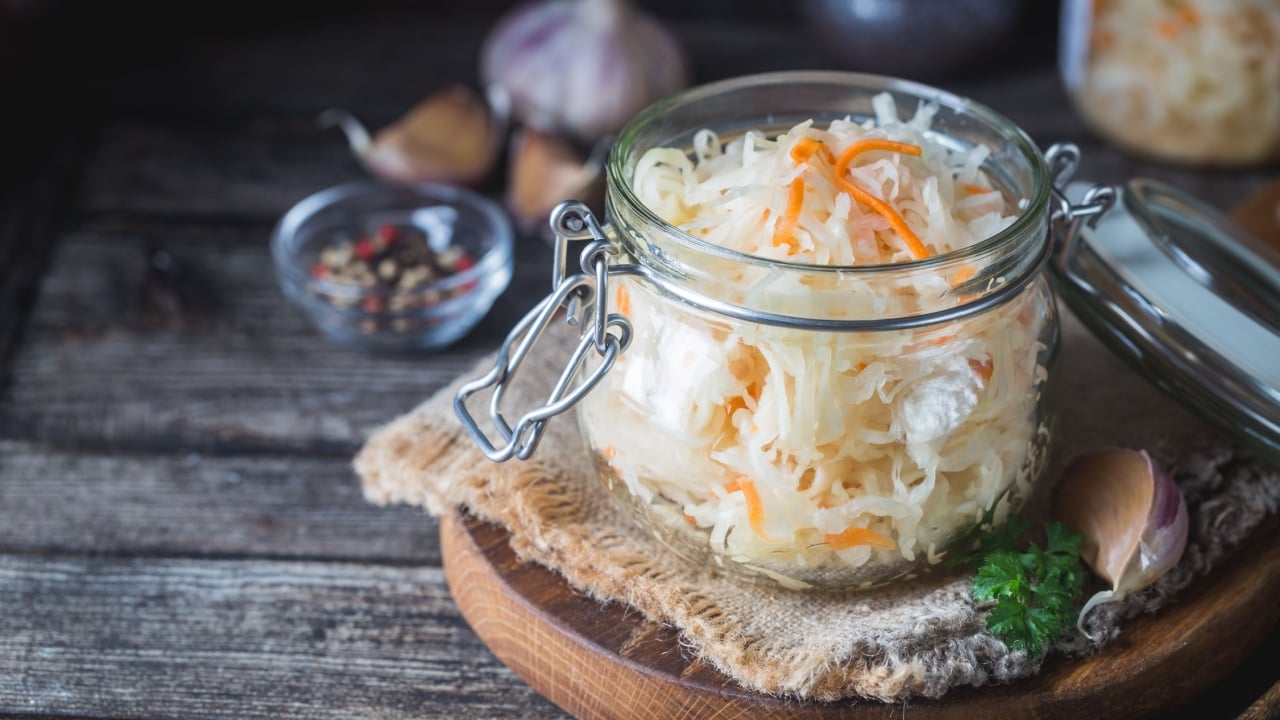 Glass jar with homemade sauerkraut on rustic wooden table