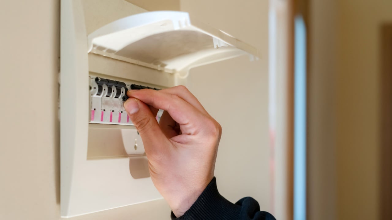 Hand switching power switch on a fusebox. Close up of electrician checking fuse box knob