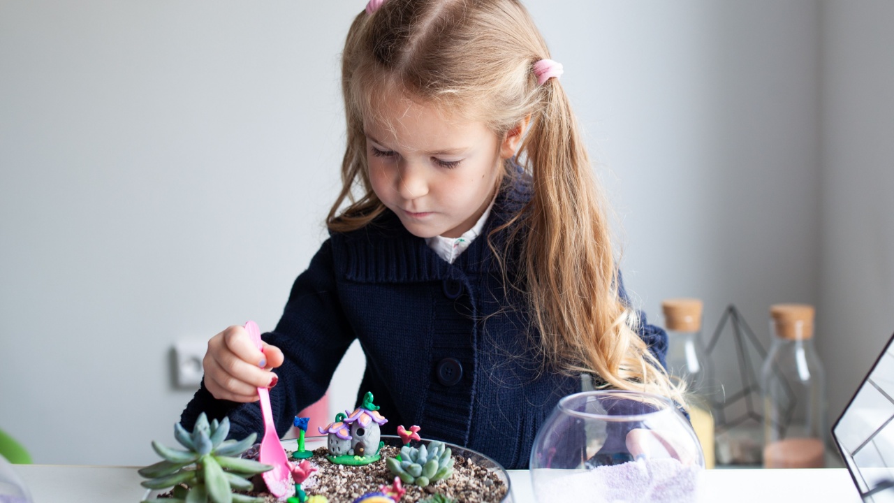 Beautiful girl plants succulents in a glass florarium at a lesson in a creativity studio