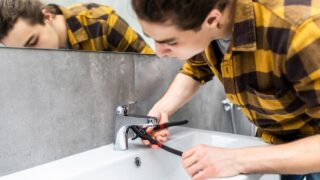 Plumber man fixing water tap with spanner