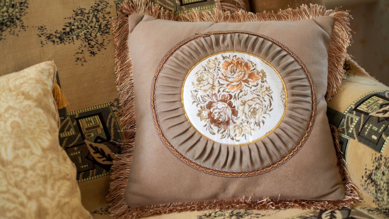 Decorative pillow with a fringe and an embroidered panel depicting roses