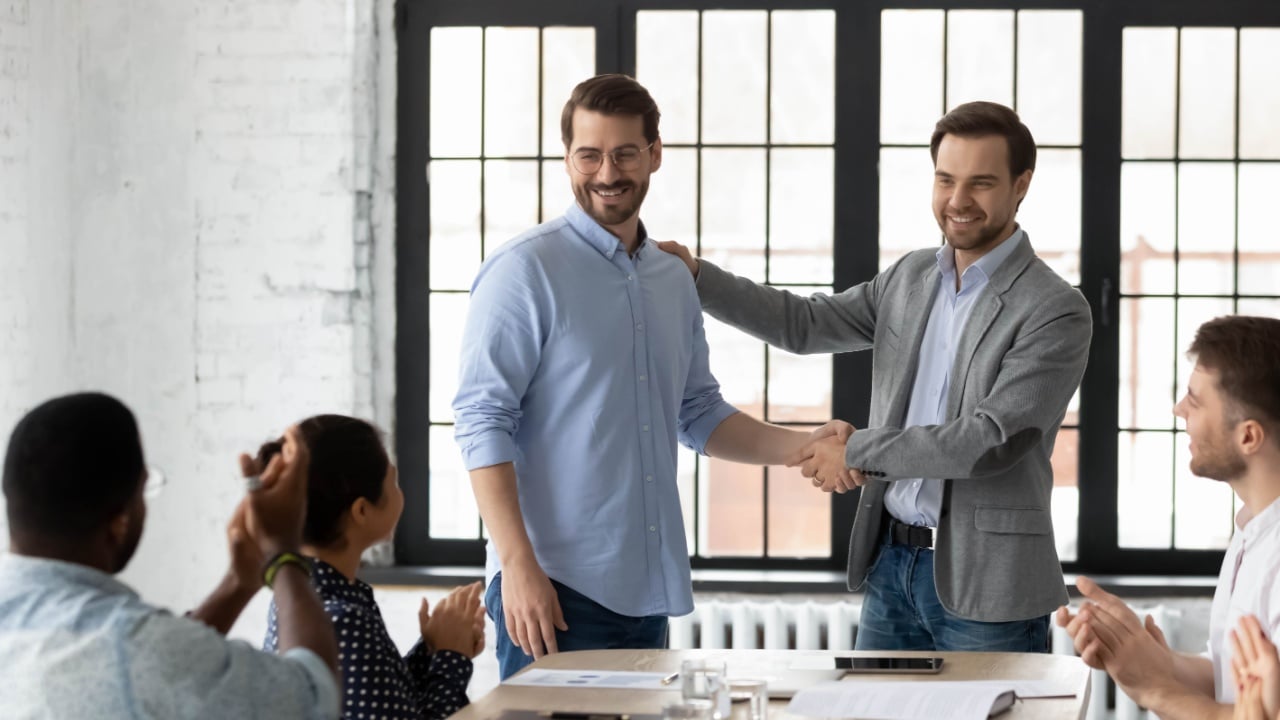 Proud boss encouraging and thanking happy employee for good job, shaking hand. Excited worker getting promotion, recognition, respect and applause of colleagues. Leader introducing new team member