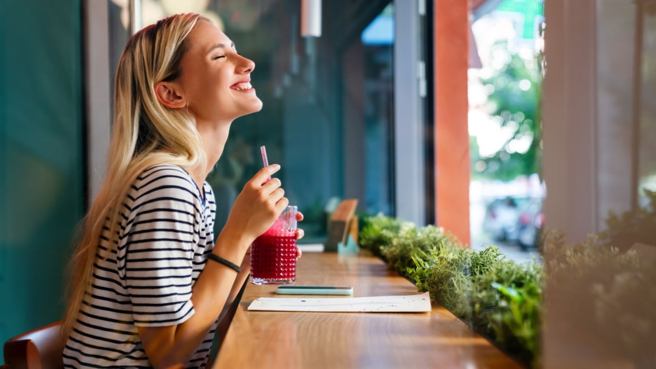 Portrait of a healthy young happy woman drinking a juice in cafe