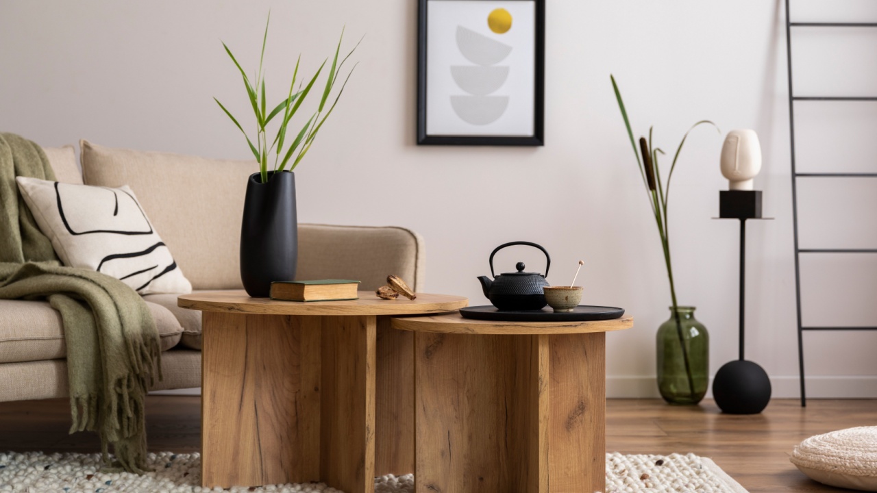 Creative composition of stylish living room with beige sofa with pillow, wooden coffee table, glass vase with dried flowers, personal accessories. Mock up poster frame. Home decor. Template.