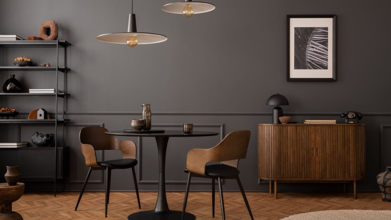 Aesthetic composition of living room interior with mock up poster frame, round black coffee table, wooden sideboard, dark wall with stucco, rug, rack and personal accessories.