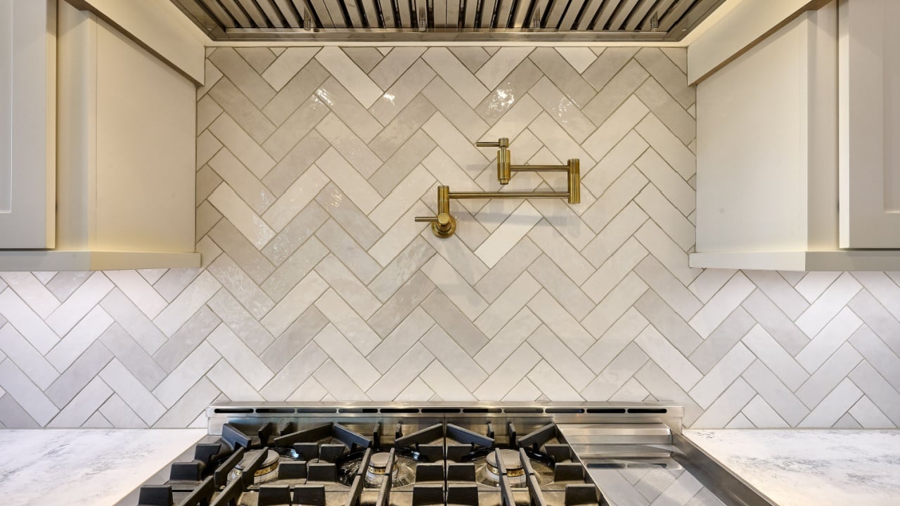 Pot filler on kitchen backsplash above gas range burners