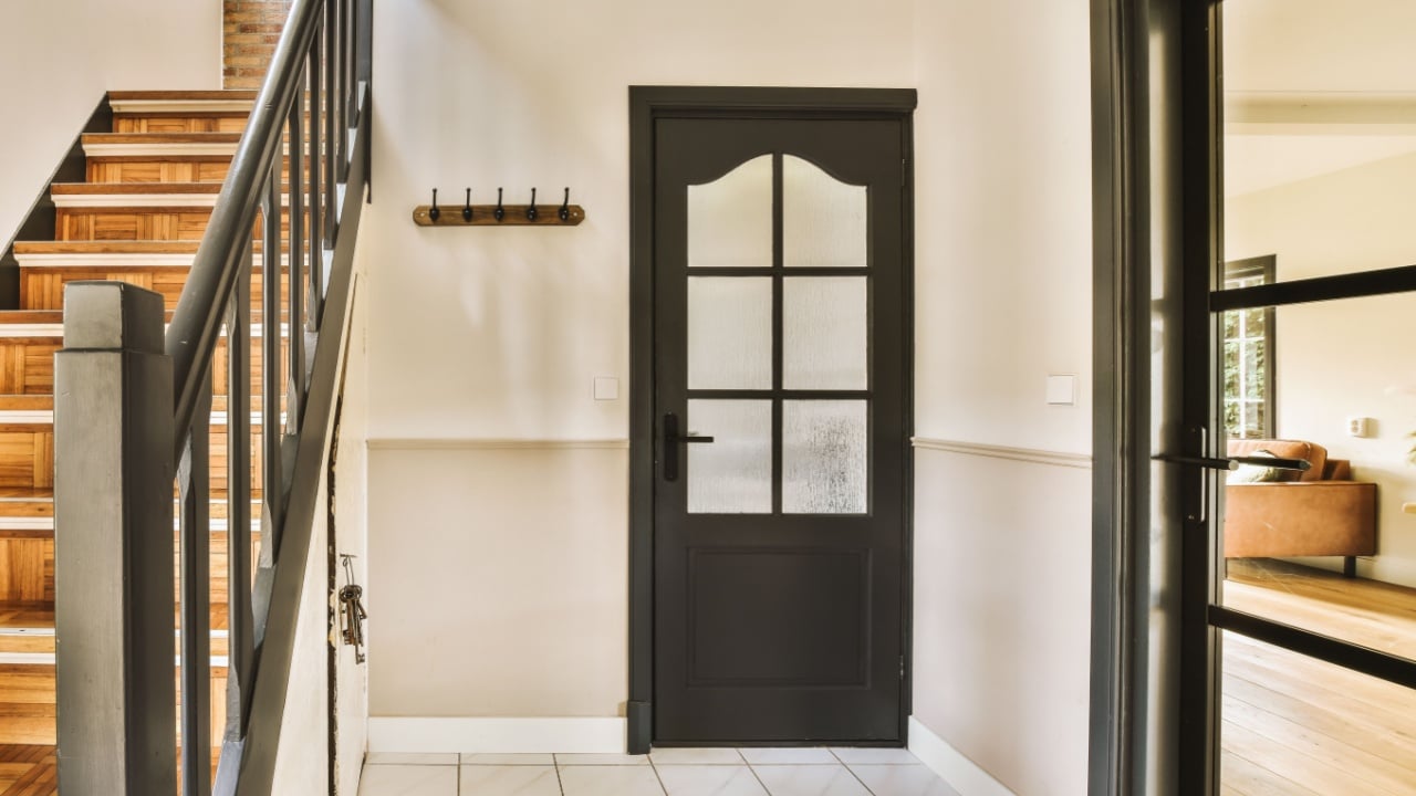 an entry way in a house with wood floors and black door leading up to the second floor