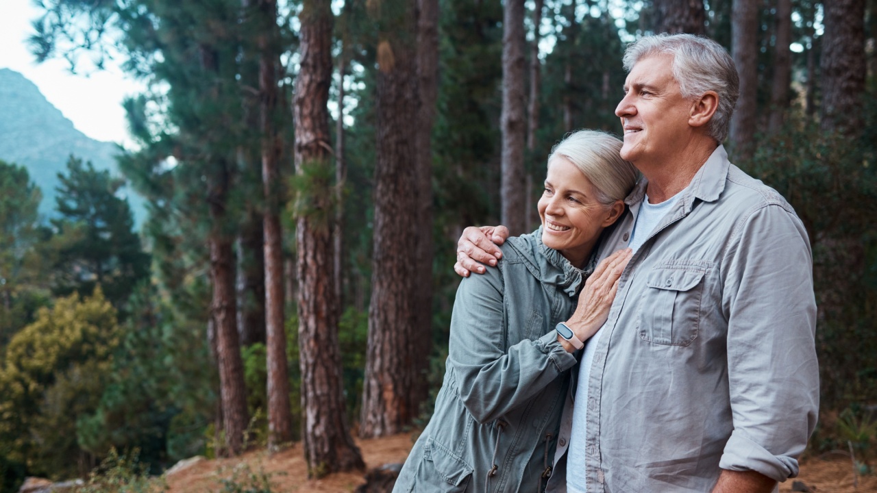 Hug, hiking and senior couple in forest, workout and quality time outdoor, happiness and wellness. Romance, mature man and old woman in woods, walking and fitness for healthy lifestyle and nature