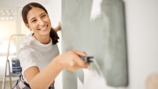 Woman, renovation and painting a home wall in DIY, house project or maintenance or construction, interior design and decoration. Paint, bedroom or remodel space with paintbrush, roller and painter