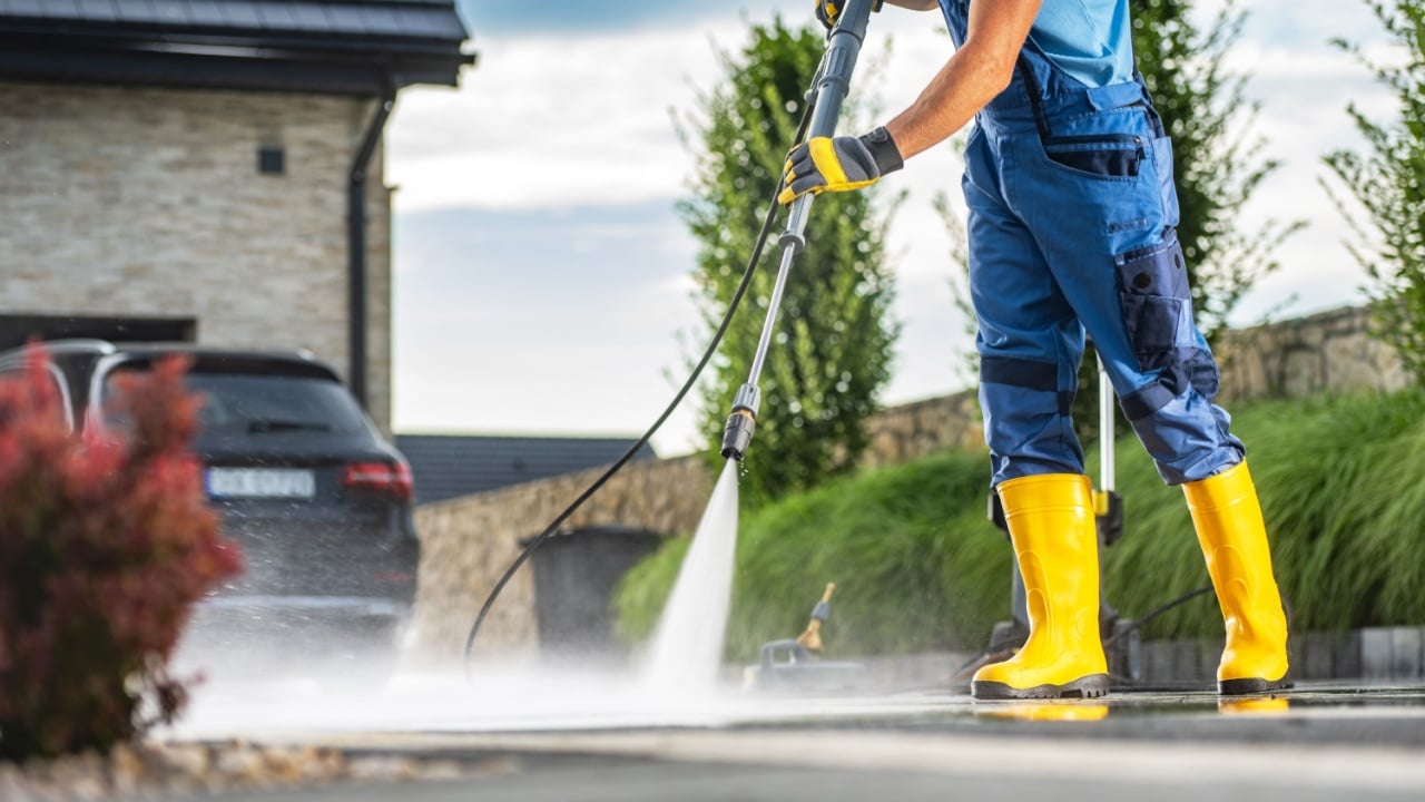 Caucasian Homeowner Using Powerful Pressure Washer to Clean Dirty Driveway