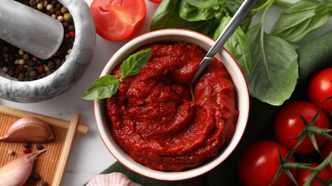 Tasty tomato paste in bowl and ingredients on table, flat lay