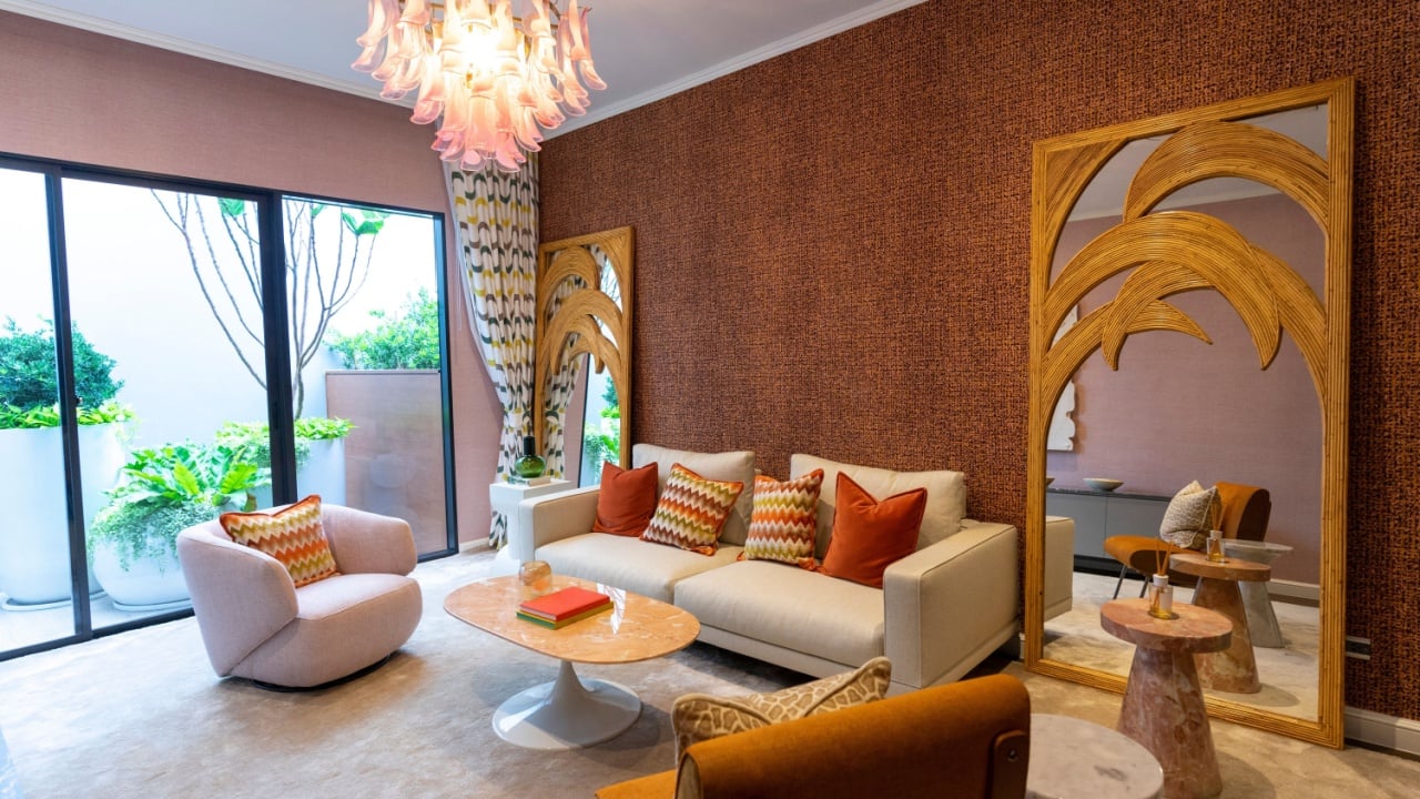 Living room in art Deco style with grey and brown upholstered designer furniture. With a large wooden mirror on wall.