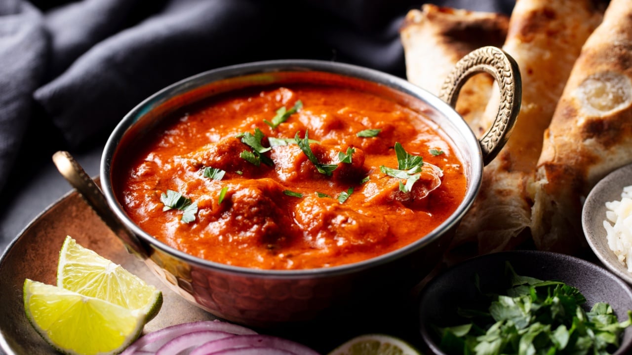 Indian curry, tikka masala, chicken, lamb, mutton Rogan Josh with rice and naan bread. Dark background. Close up.