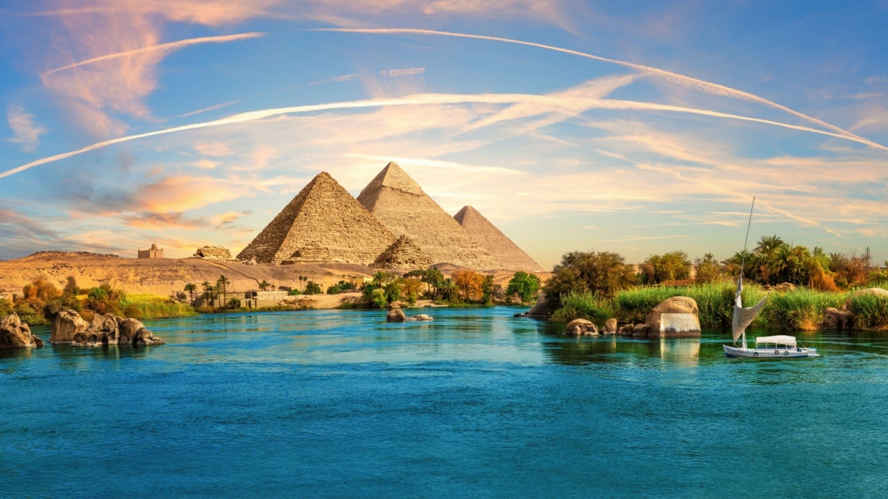 Lonely Saleboat in the Nile river and ancient rocks in the Aswan desert by the pyramids, Egypt