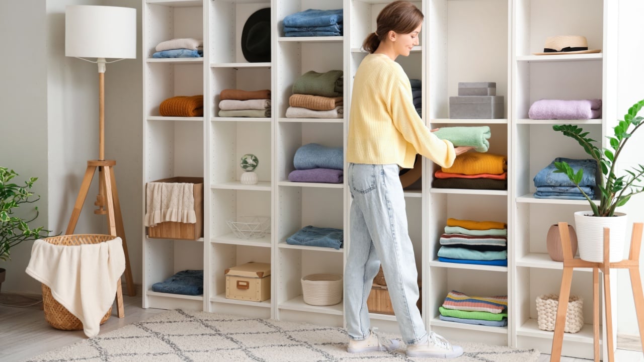 Young woman organizing clothes at wardrobe