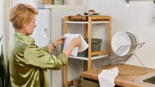Beautiful senior woman harmoniously organizes kitchen linens in a warm and inviting space.