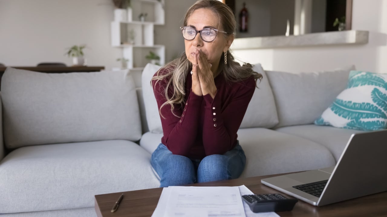 Stressed with finances. Pensive worried aged lady entrepreneur or retiree manage financial papers at home office with calculator pc plan risky investment feel nervous about debt bankruptcy possibility