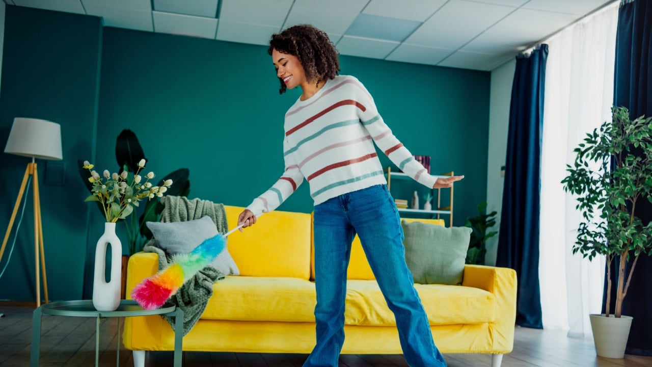 Woman cleans colorful living room with a rainbow duster in a bright home interior showing casual lifestyle and cozy modern decor