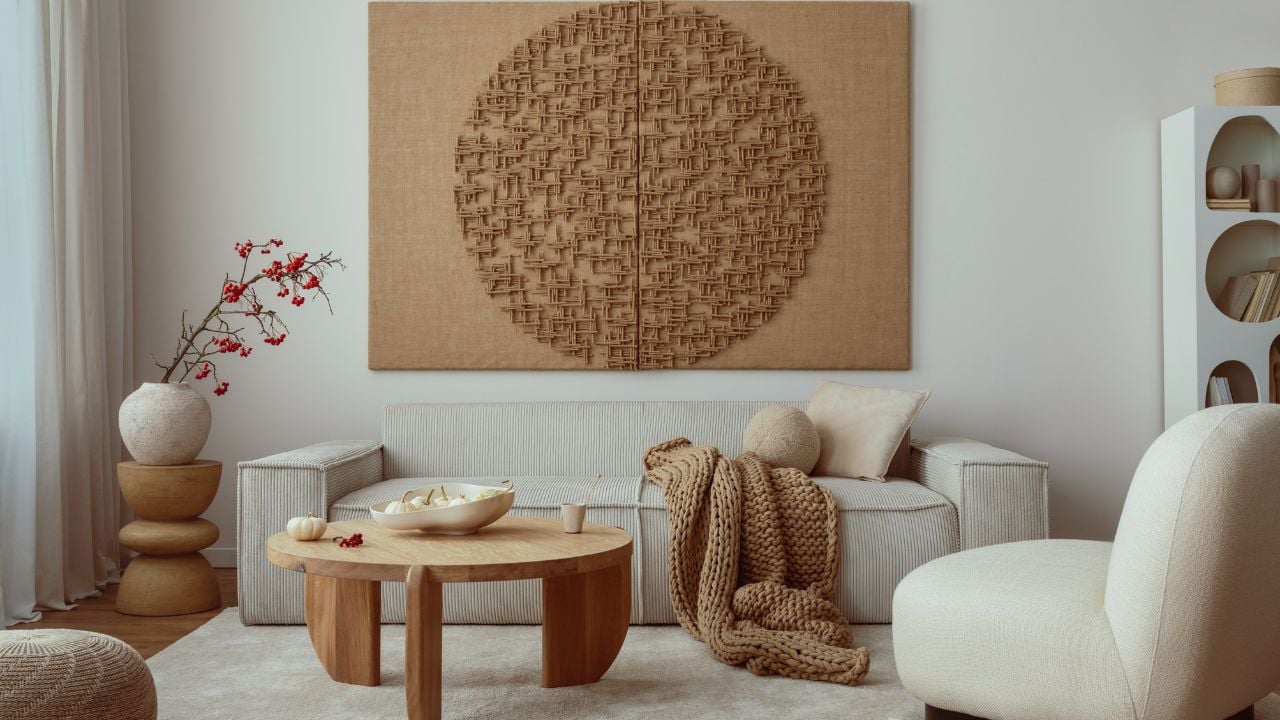 Creative composition of living room interior with mock up poster frame, beige sofa, wooden coffee table, rounded shapes armchair, vase with rowanberry and personal accessories. Home decor.