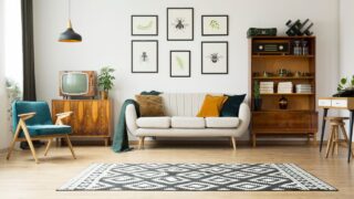 Vintage tv standing on a wooden cabinet next to a comfy couch in a stylish day room interior