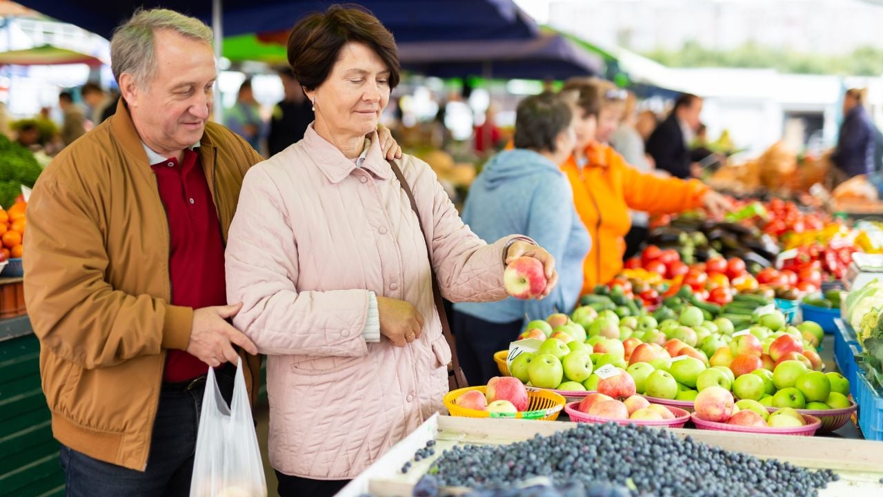 Elderly man and a woman buy apples