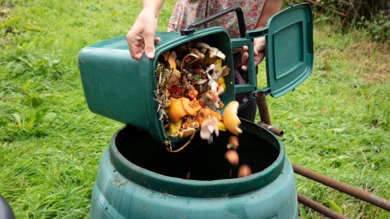 A woman emptying a home composting bin into an outdoor compost bin to reduce waste