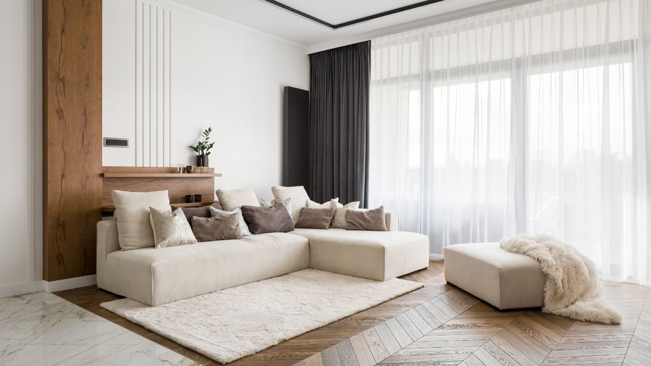 Elegant and comfortable designed living room with big corner sofa, wooden floor and big windows