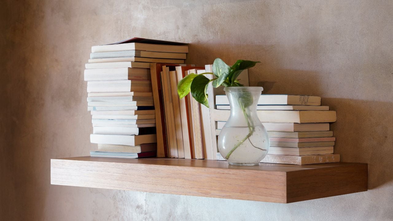 Stack of books on floating wooden bookshelf. Education and knowledge concept. Pile of books to read. House interior decoration
