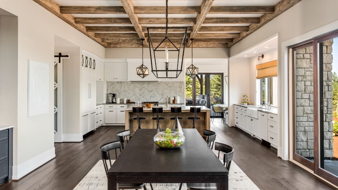 Stunning Dining room and Kitchen in New Luxury Home. Wood beams and elegant pendant lights accent the beautiful open floor plan, dining room, and kitchen.
