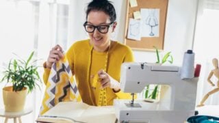 Woman sewing on a sewing machine at her home. Woman seamstress work on the sewing-machine